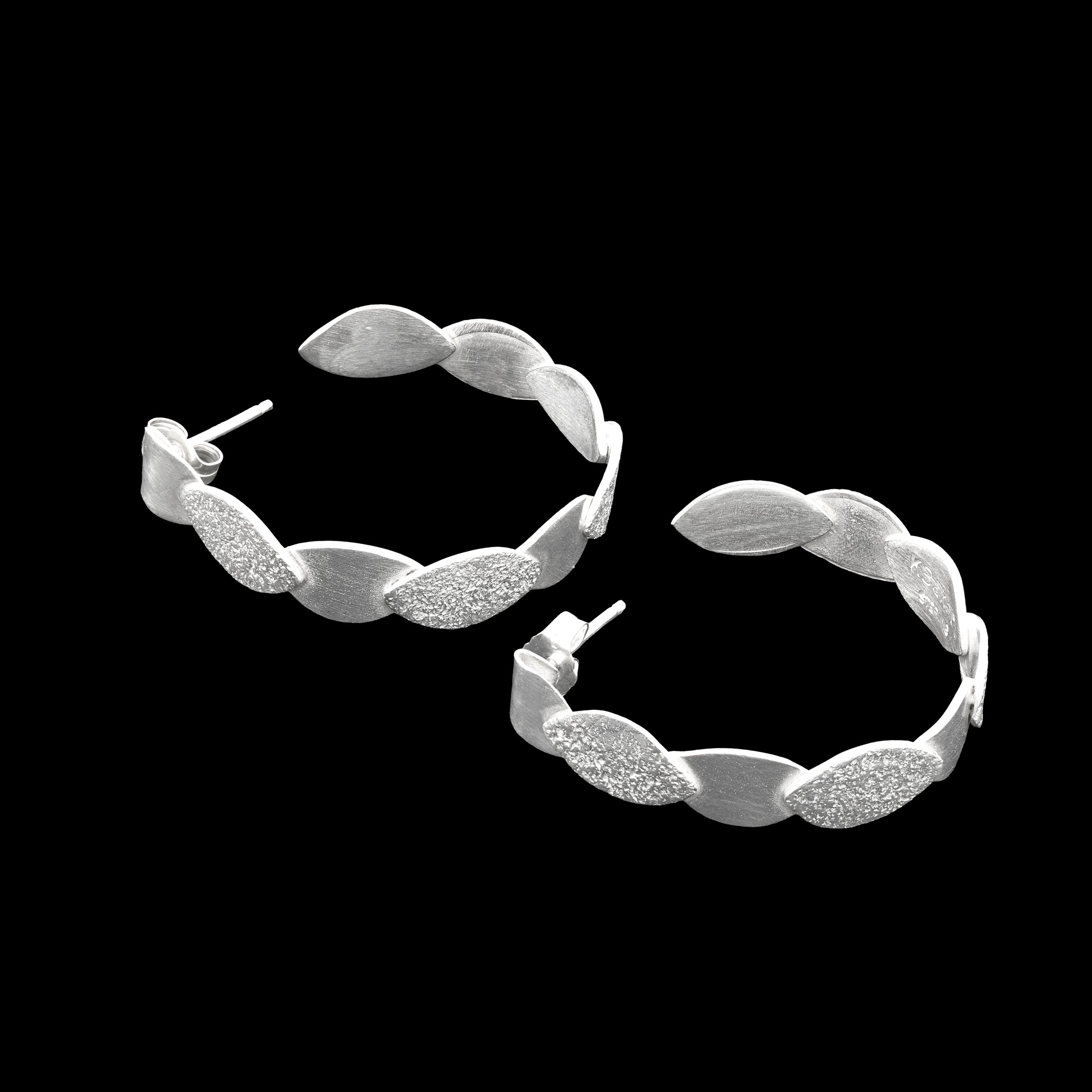 Hand-fabricated, sterling silver post hoops of textured and shiny leaves.