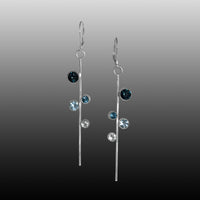 Contemporary linear drop earrings, hand-fabricated in sterling silver with asymmetrically arranged topaz gemstones in shades of blue.