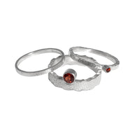 Hand-fabricated, sterling silver ring highlighted by a 4mm deep garnet red gemstone.  Shown with accent rings.