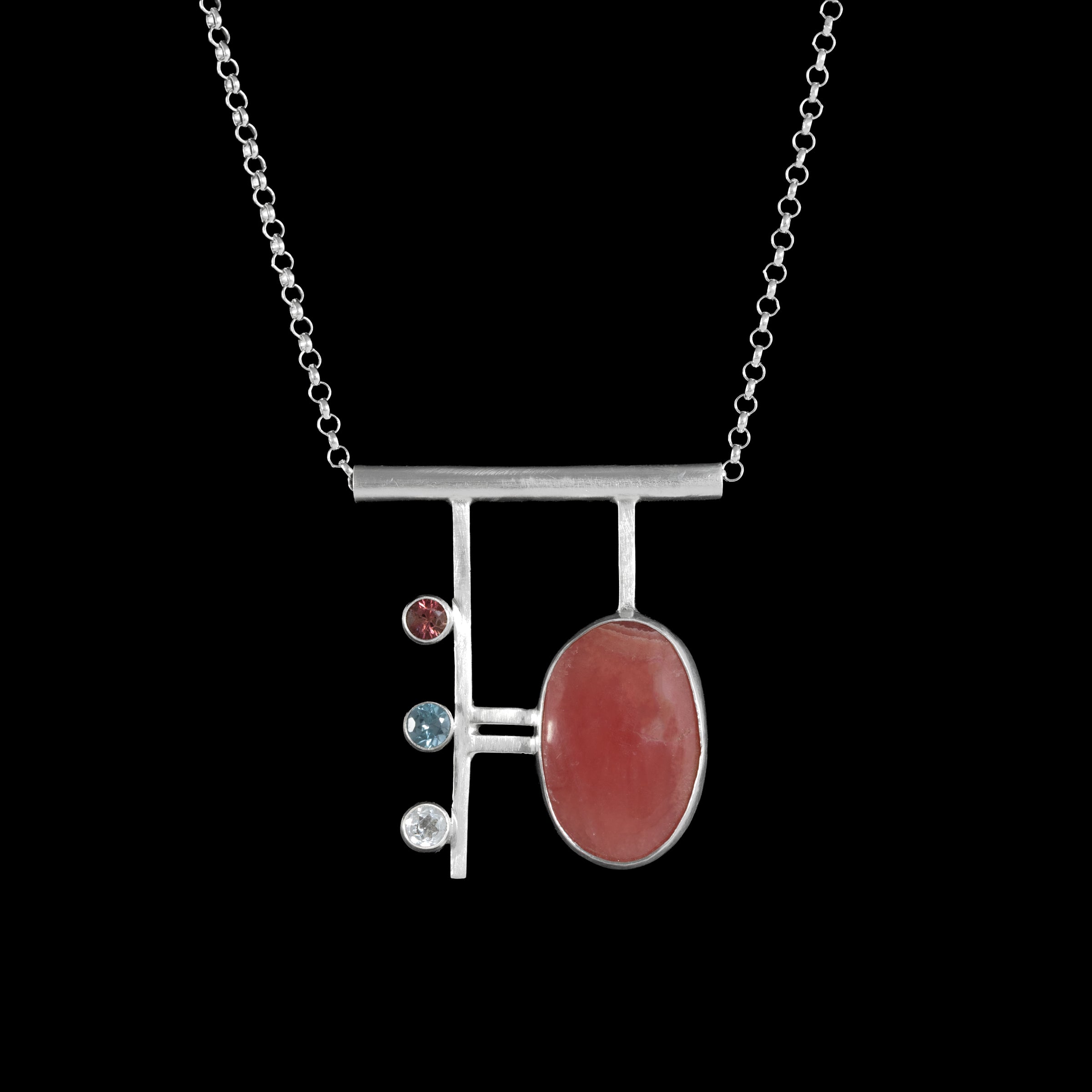 Contemporary, geometric design pendant necklace, hand-fabricated from sterling silver and featuring a large rhodochrosite cabochon highlighted with a pink tourmaline, blue zircon and white topaz.