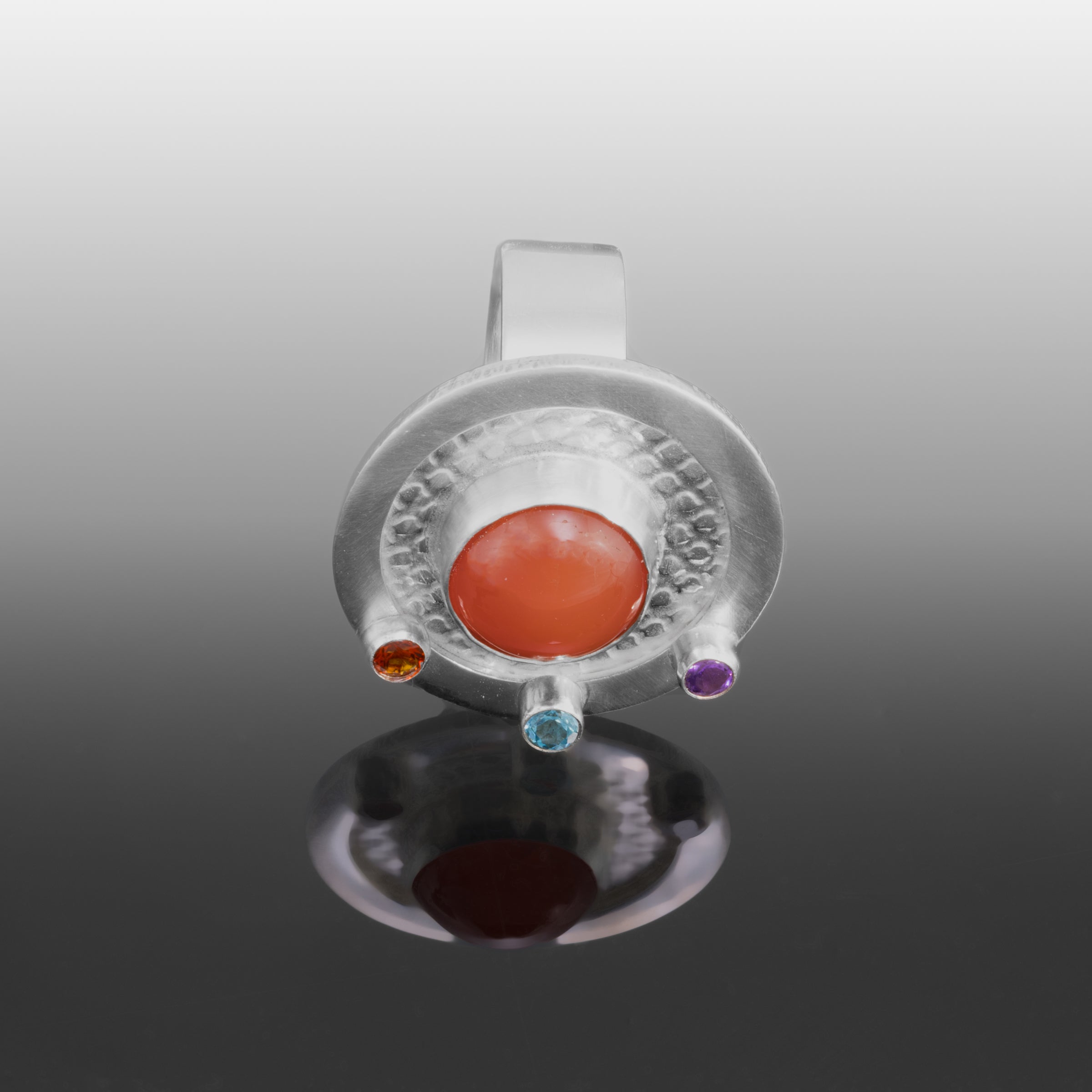 One-of-a-kind, statement ring in sterling silver with a 10mm orange chalcedony cabochon surrounded by three faceted stones – a fire citrine, London blue topaz and purple amethyst.  Size 8.