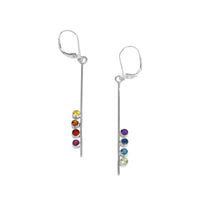 Asymmetrical, sterling silver earrings set with pride-themed faceted stones – pink tourmaline, red garnet, Mexican fire opal, golden citrine, green peridot, sky blue topaz, London blue topaz and purple amethyst.