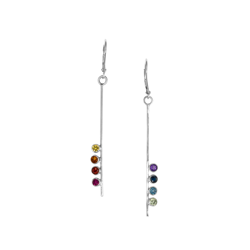 Asymmetrical, sterling silver earrings set with pride-themed faceted stones – pink tourmaline, red garnet, Mexican fire opal, golden citrine, green peridot, sky blue topaz, London blue topaz and purple amethyst.