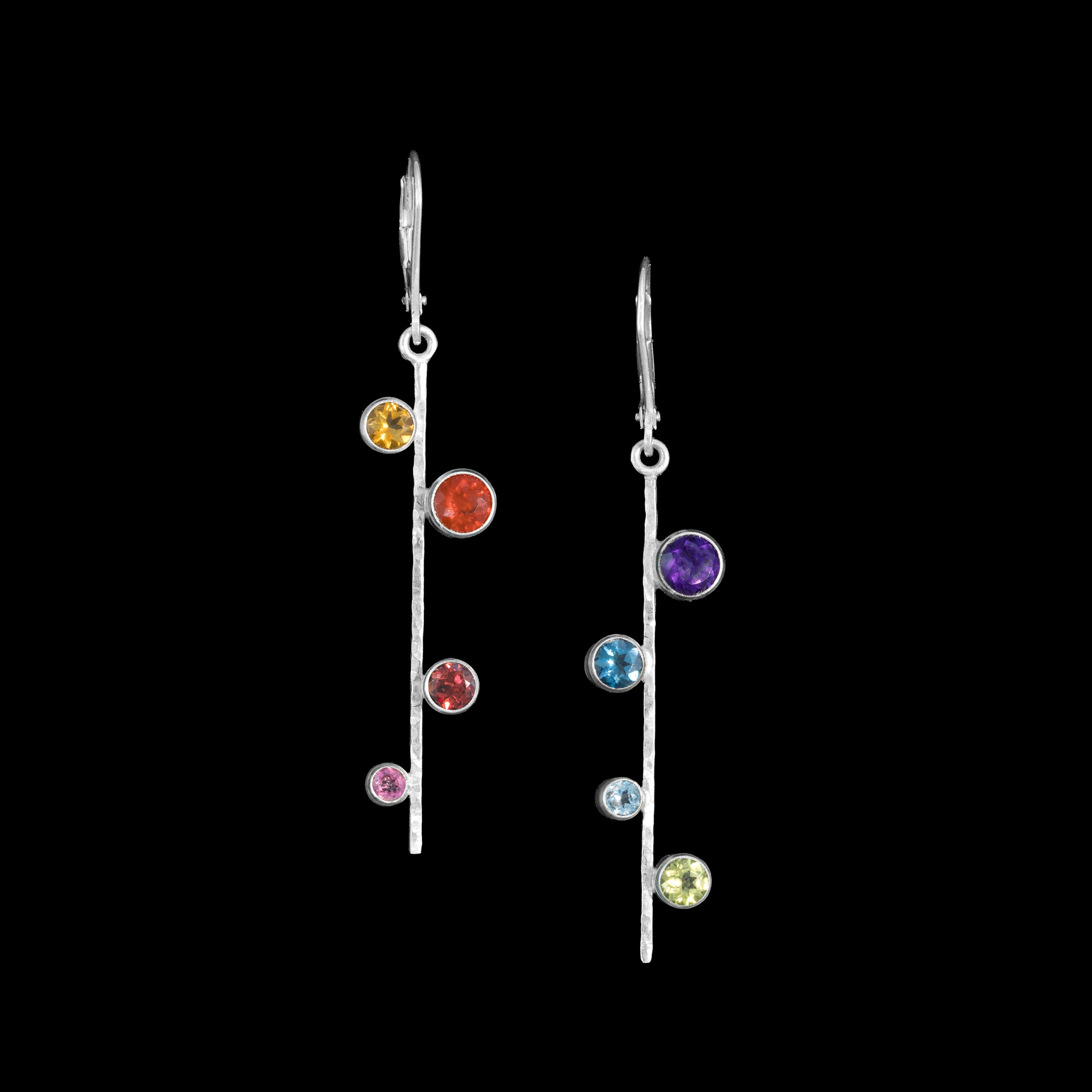 Asymmetrical, sterling silver earrings set with pride-themed faceted stones – pink tourmaline, red garnet, Mexican fire opal, golden citrine, green peridot, sky blue topaz, London blue topaz and purple amethyst.