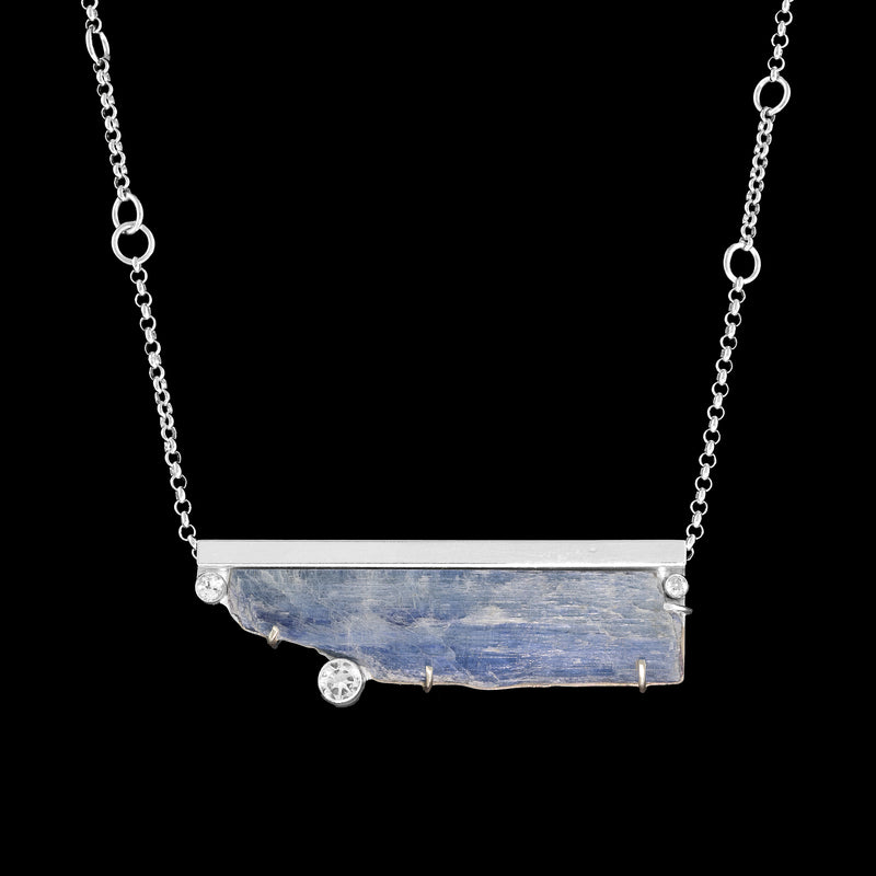 Contemporary, one-of-a-kind pendant necklace, handcrafted from a blade of blue Kyanite, framed in sterling silver and accented by three white topaz stones.  Sterling silver rolo chain.