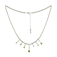 Contemporary design necklace, hand fabricated from Argentium sterling silver tubes and rings and set with four green peridots and three white topaz gemstones. 