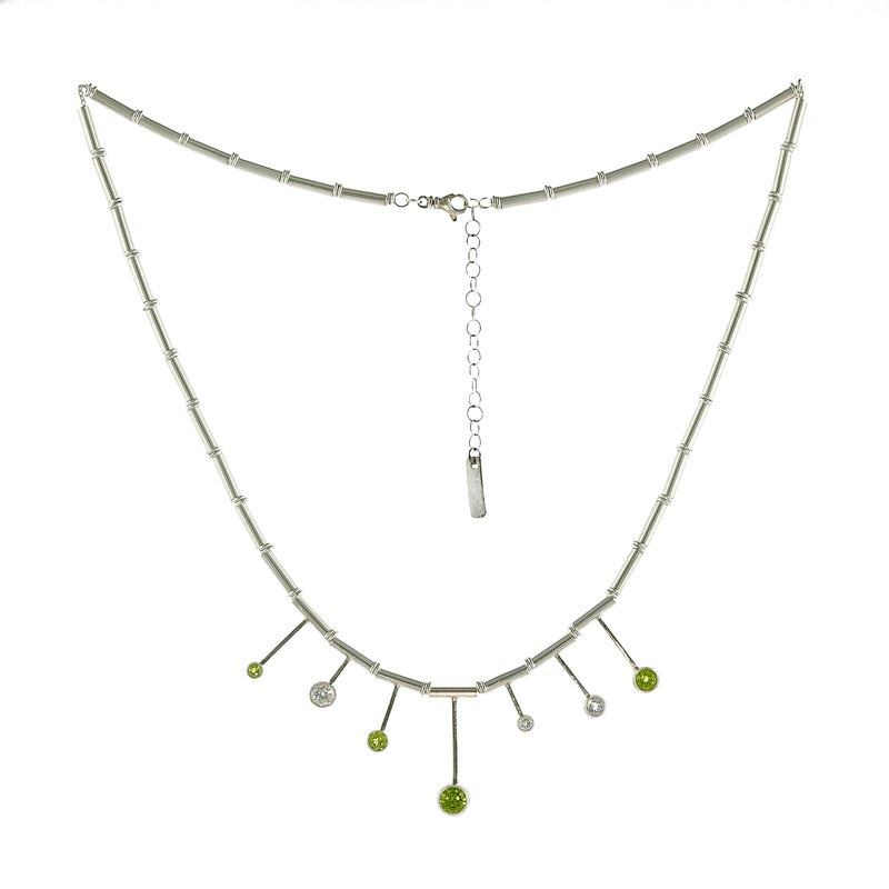 Contemporary design necklace, hand fabricated from Argentium sterling silver tubes and rings and set with four green peridots and three white topaz gemstones. 