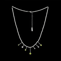 Contemporary design necklace, hand fabricated from Argentium sterling silver tubes and rings and set with four green peridots and three white topaz gemstones. 