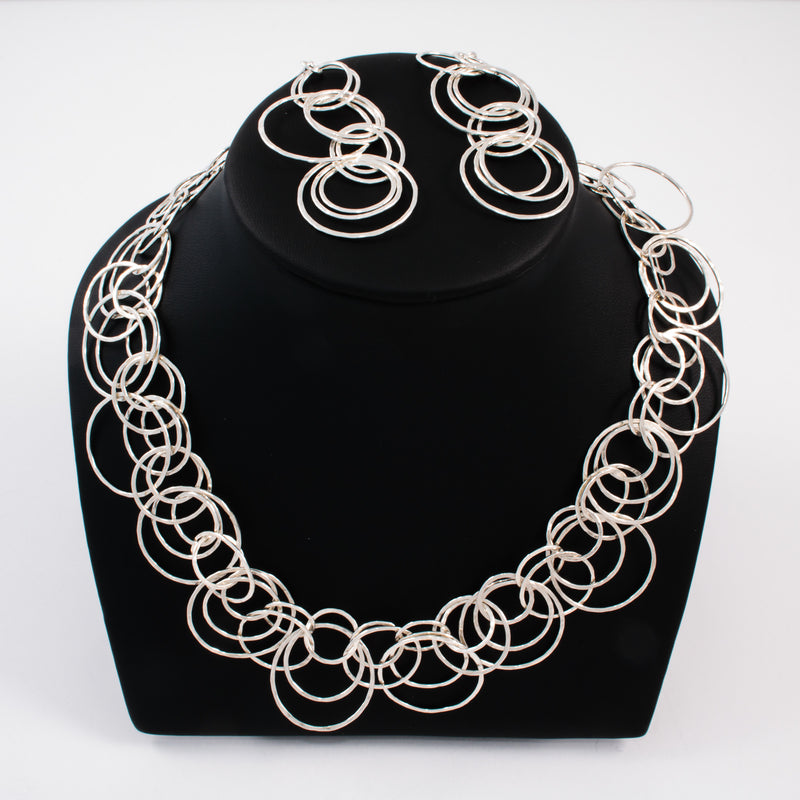 Statement necklace handcrafted from dozens of hammered rings of Argentium sterling silver.  Shown with matching earrings.