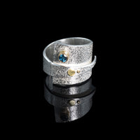 Contemporary sterling silver wrap ring with 14k gold elements and a 4mm London blue topaz set in 14k gold.