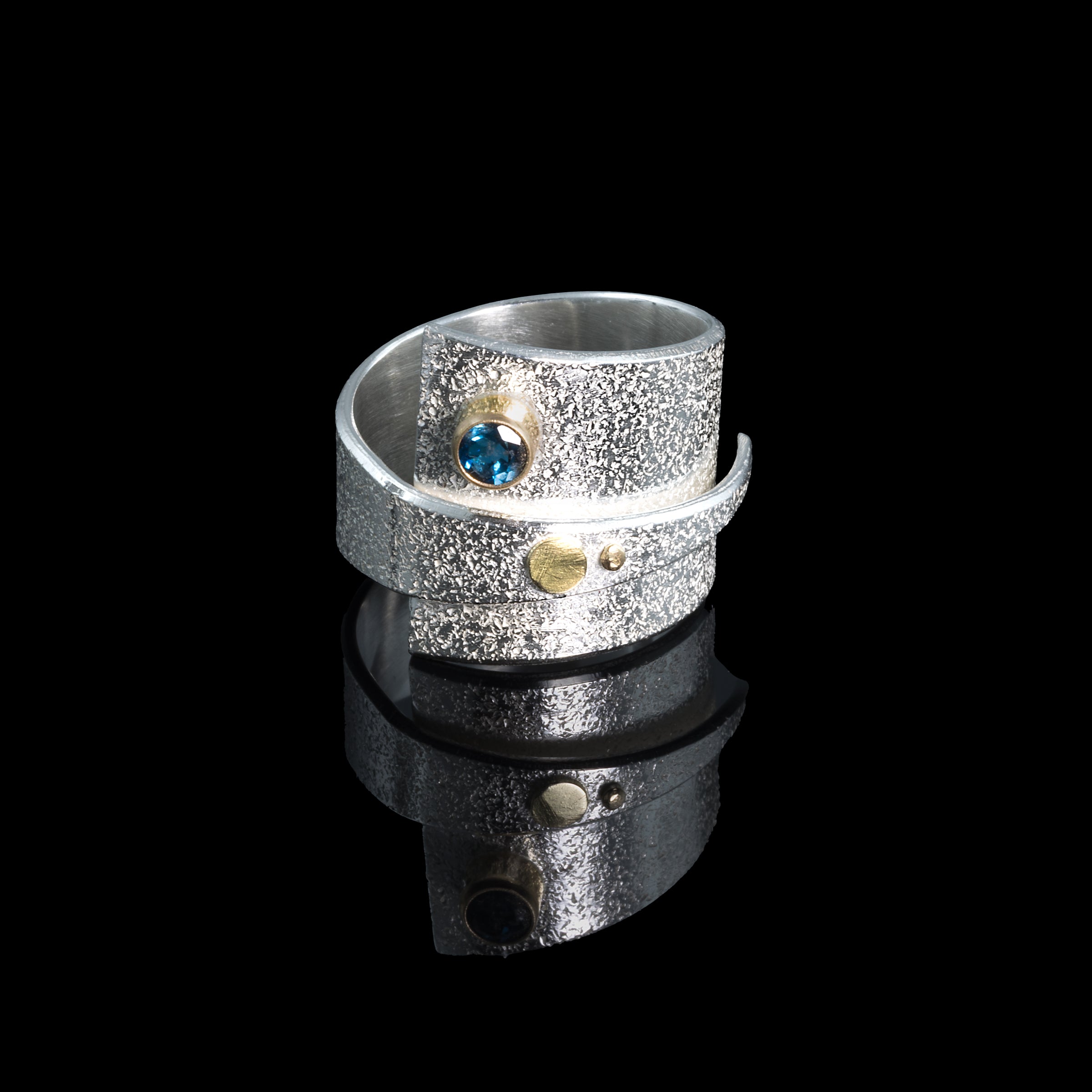 Contemporary sterling silver wrap ring with 14k gold elements and a 4mm London blue topaz set in 14k gold.