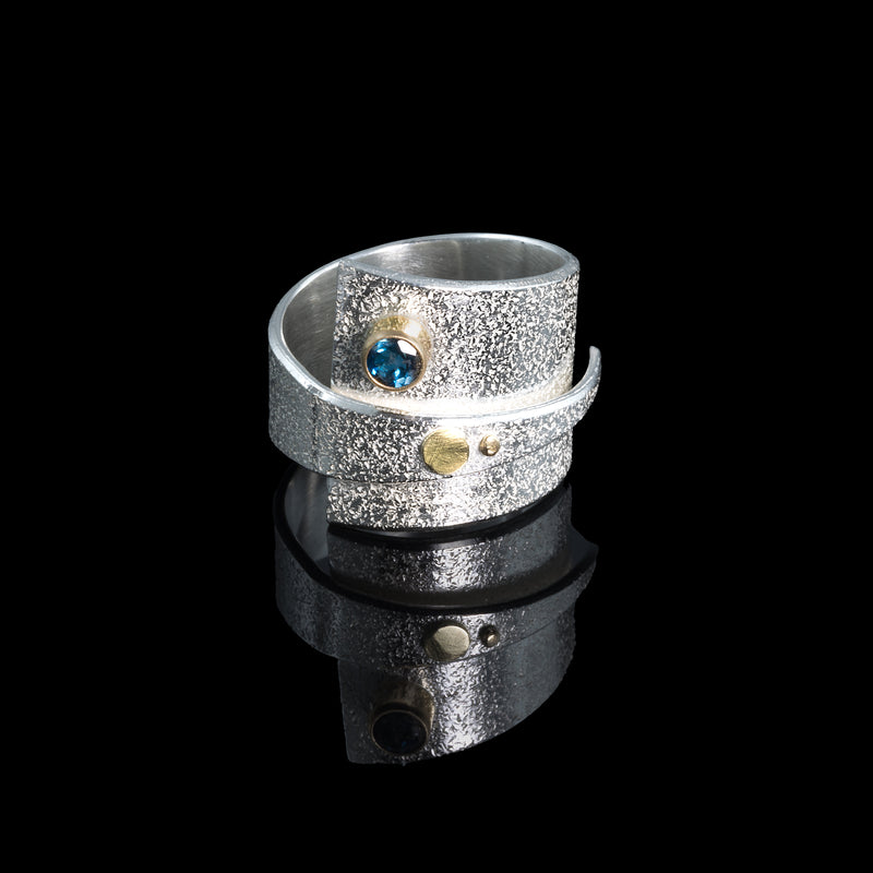 Contemporary sterling silver wrap ring with 14k gold elements and a 4mm London blue topaz set in 14k gold.