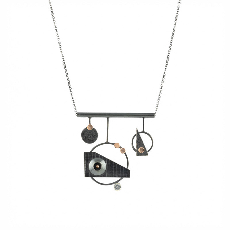 Modern industrial design pendant necklace, handcrafted from oxidized Argentium sterling silver with 14K rose gold elements and set with a white sapphire.