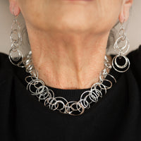 Statement necklace handcrafted from dozens of hammered rings of Argentium sterling silver.  Shown with matching earrings.