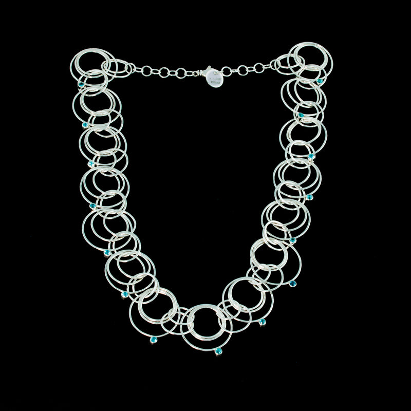 Statement necklace handcrafted from dozens of hammered rings of Argentium sterling silver and set with 15 3mm blue zircons.