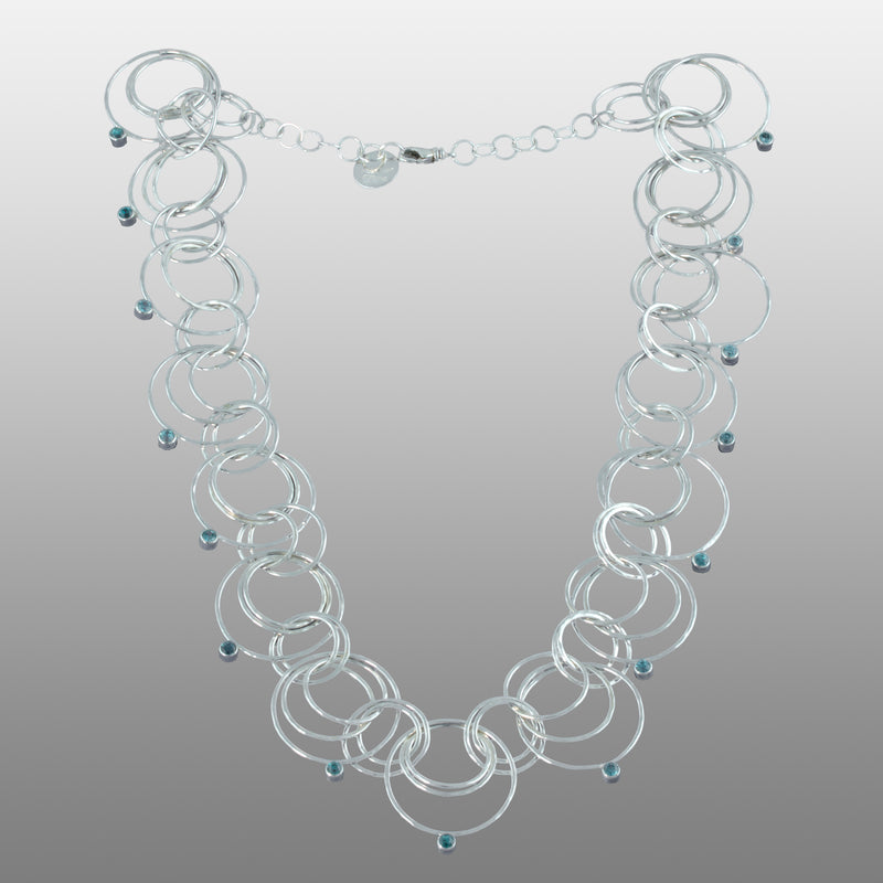 Statement necklace handcrafted from dozens of hammered rings of Argentium sterling silver and set with 15 3mm blue zircons.